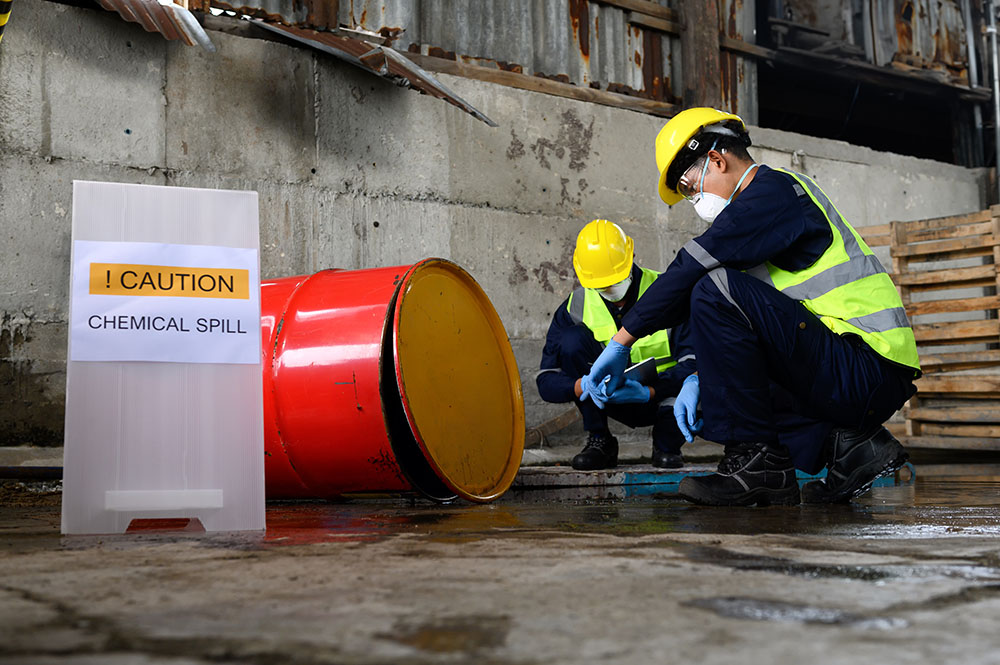 Two Officers with Masks inspecting chemicals spilled on the ground, caution label chowing the concept of how to manage chemical spills 